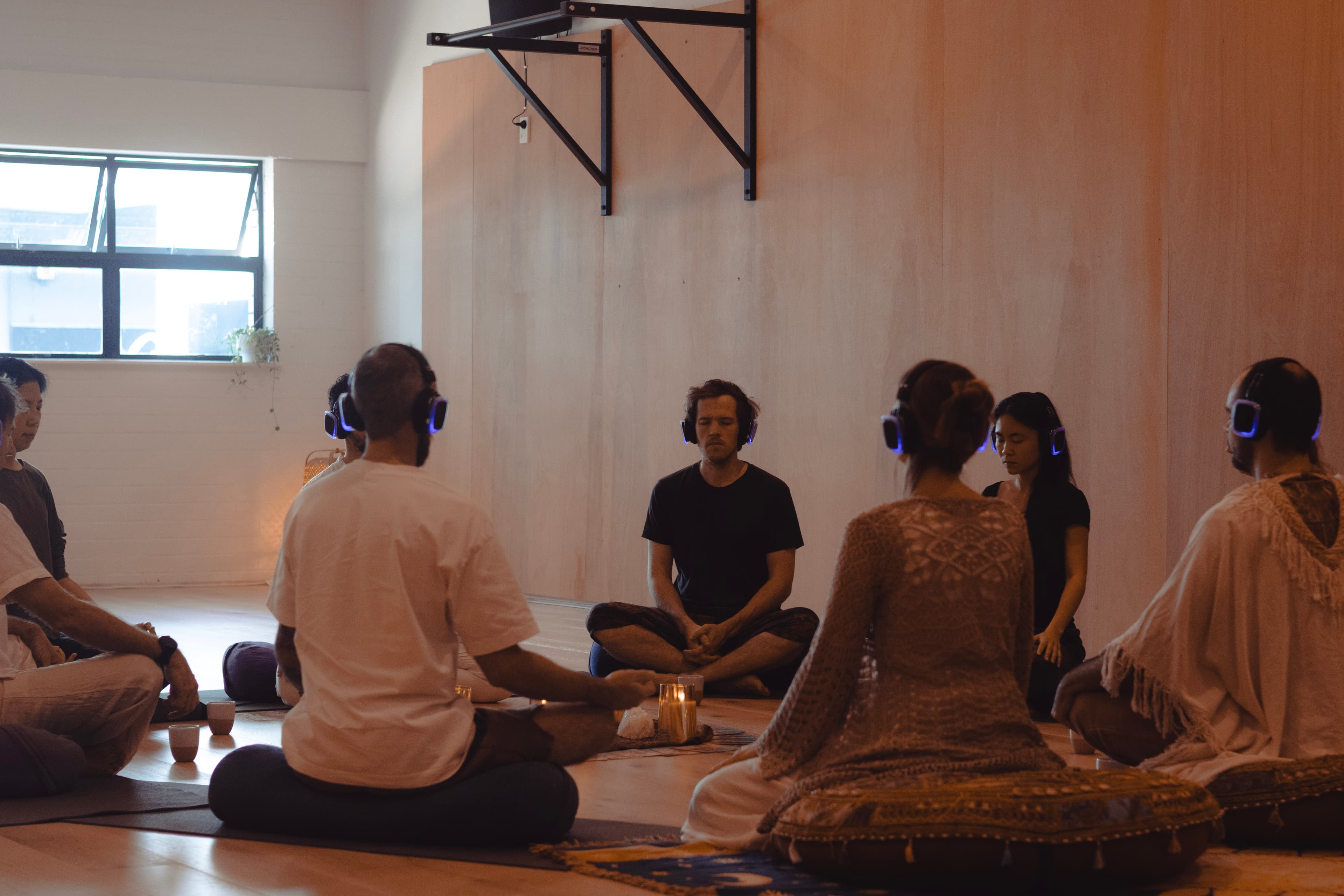 Group of Silent Rave attendees meditating together in a circle, wearing wireless headphones